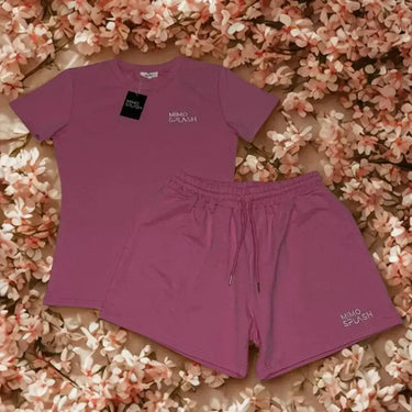 Coordinated activewear sets featuring a matching pink t-shirt and shorts on a floral backdrop.