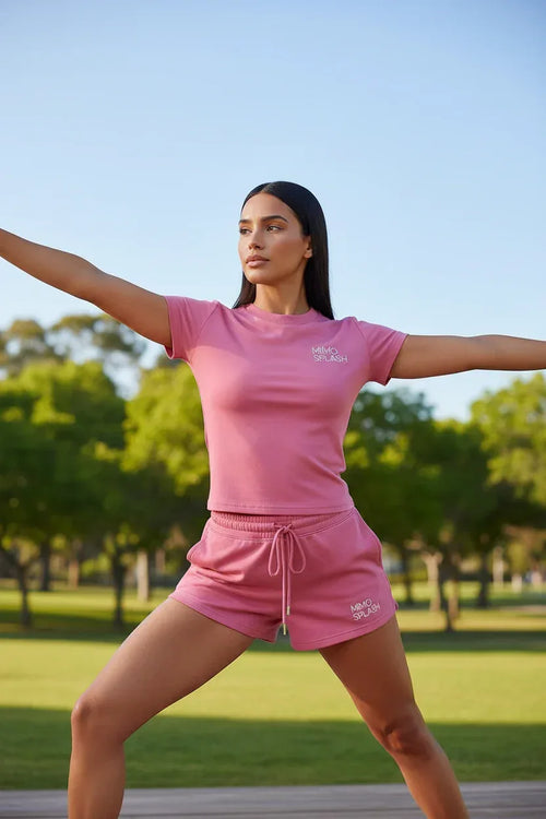 Model wearing MIMOSPLASH pink crop top and shorts set, showcasing premium activewear in a park.